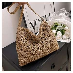 Détail du motif floral crocheté à la main et zip métallique sur le sac bandoulière en paille