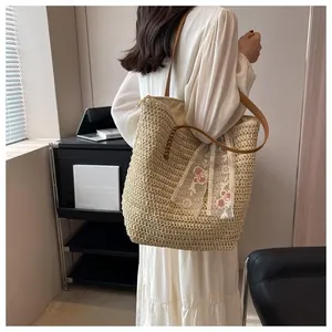 Detail of beige straw tote bag with brown leather handles and pink floral lace scarf decoration
