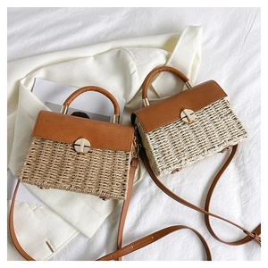 Detail of woven straw handbag featuring premium leather flap and gold metal buckle
