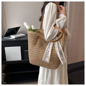 Detailed macro view of woven straw tote bag with brown leather handle and floral lace scarf