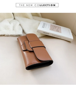 Detail of a brown matte leather long wallet with overlapping flap and black edge finish