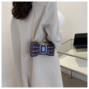 Détail d'un sac pochette nœud violet avec cadre en métal doré et bandoulière chaîne