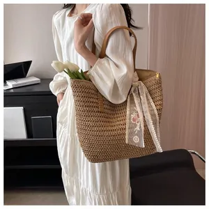 Detailed view of large straw tote bag with brown leather handles and lace floral scarf