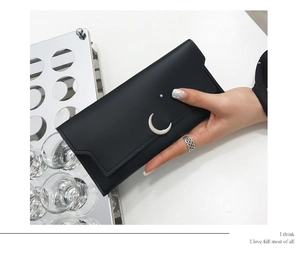 Détail du portefeuille long en cuir mat noir avec ornements métalliques lune et étoiles