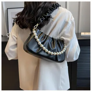 Detail of black pleated cloud bag with large pearl chain strap worn by a model