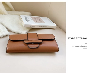 Detail view of brown leather long wallet with wide strap snap closure and sleek edges