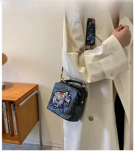 Détail du sac éléphant brodé noir vintage avec bandoulière large à motifs et boucles dorées