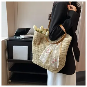 Close-up of a woven straw tote bag with white lace ribbon and brown leather straps