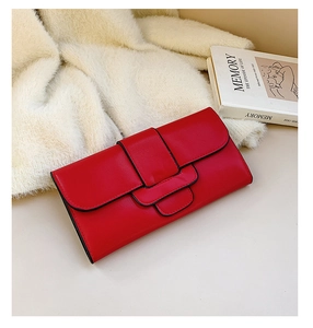 Detail of red minimalist long clutch purse on textured fabric with a stylish art book