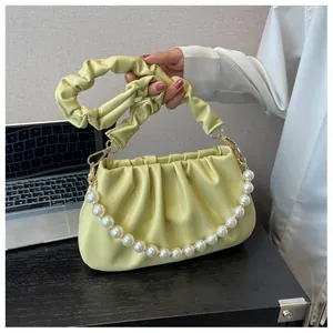 Detail of light green pleated cloud bag featuring premium pearl strap and soft leather folds