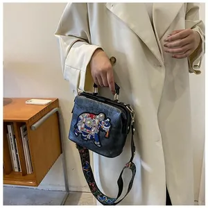 Détail de la broderie éléphant et de la bandoulière large sur un sac rétro chic