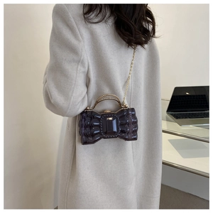 Gros plan sur la pochette nœud en résine violette avec poignée en strass et chaîne d'or