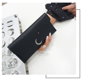 Détail du portefeuille noir en similicuir avec accents métalliques de lune et d'étoile