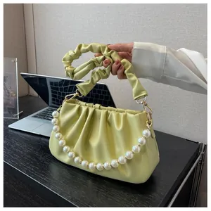 Detail of soft pleated cloud bag featuring decorative pearl chain and ruched strap