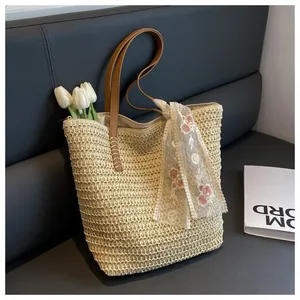 Close-up of straw tote bag with brown leather handles and delicate floral lace scarf