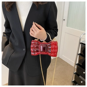 Détail du sac noeud rouge rubis transparent avec chaîne dorée et texture ondulée unique