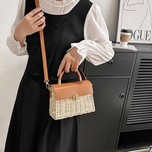 Fashionable woven straw crossbody bag with brown leather accents and gold metal clasp