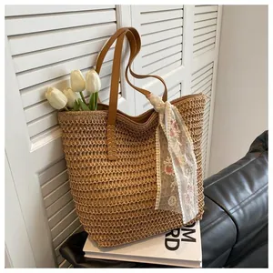 Detail of hand-woven straw tote bag with brown leather handles and lace scarf detail