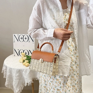 Women's woven crossbody bag with brown leather trim and gold twist lock in lifestyle setting