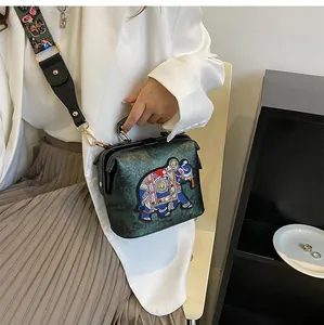 Détail de la broderie d'éléphant sur un sac bandoulière vert foncé avec sangle à motifs
