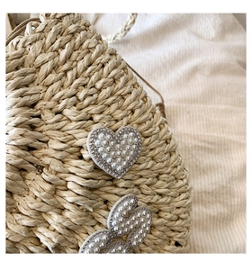 Détail du sac en paille avec patchs cœur, perles fantaisie et bordures en strass