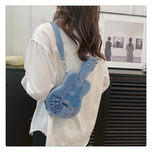 Detailed view of guitar-shaped denim shoulder bag with metal studs and embroidery