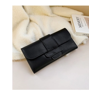 Detail of minimalist black faux leather clutch with snap closure on cozy textured fabric