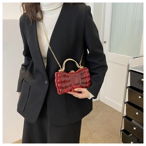 Détail de la pochette nœud rouge en acrylique avec anse dorée sur un blazer noir