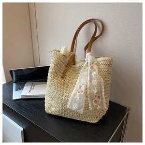 Detail of beige straw tote bag with crochet texture, brown leather handles and floral lace scarf