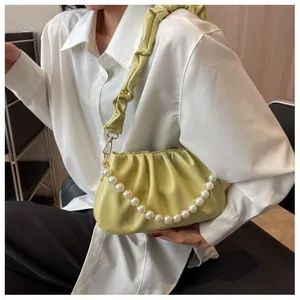 Detail of soft pleated cloud bag in pale green with pearl chain on model shoulder