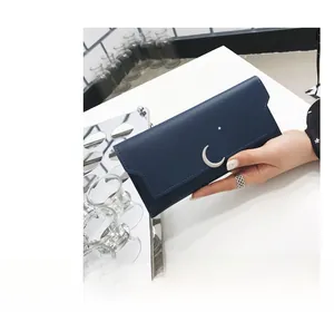 Détail du portefeuille long bleu marine avec lune et étoile tenu à la main en gros plan