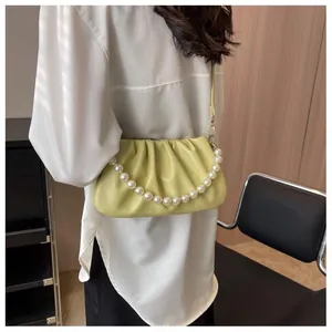 Close-up of soft pleated cloud bag with elegant pearl chain and light green leather texture
