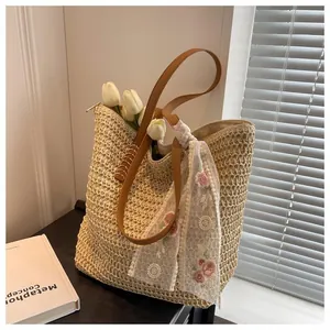 Macro detail of hand-woven straw tote with brown leather handles and floral scarf