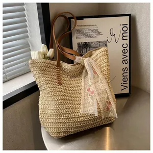 Detail of hand-woven straw tote bag featuring brown leather straps and floral lace scarf