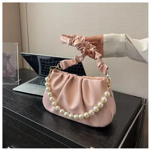 Detail of pink pleated cloud bag featuring large pearl handle and soft PU leather texture