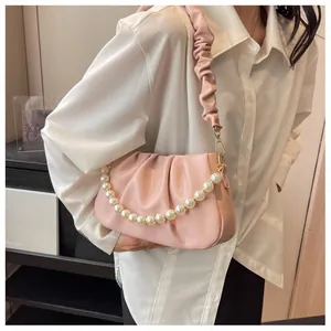 Detail of pink pleated cloud bag featuring large pearl chain and soft leather texture