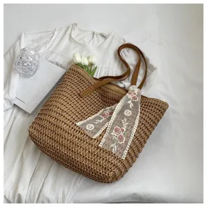 Detail of straw woven tote bag with floral lace scarf and brown leather handle