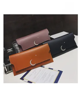 Détail de trois portefeuilles longs en violet, noir et orange avec étoiles et lunes