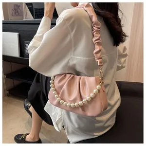 Detail view of pink pleated cloud bag with elegant pearl chain and soft leather texture