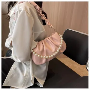 Detail of pink ruched cloud bag featuring decorative large pearl chain and soft leather strap