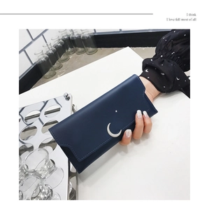 Détail d'un long portefeuille bleu marine avec croissant de lune et étoile d'argent