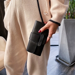 Minimalist black matte leather long clutch bag held by hand in a modern setting