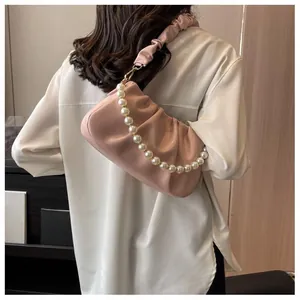 Detail of pink pleated cloud bag with pearl chain shown on white shirt outfit