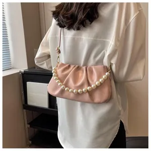 Pink pleated cloud bag with large pearl handle and adjustable strap worn on shoulder