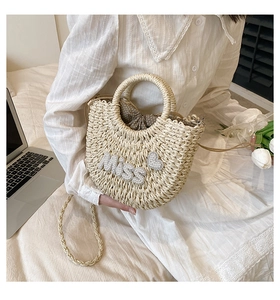 Détail d'un sac demi-lune tressé beige avec inscription Miss en perles et cœur