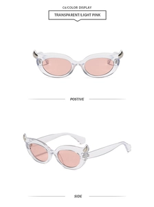 Close-up of cat eye sunglasses with devil horn accents and light pink lenses