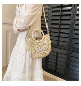 Détail d'un sac en paille tressé main avec lettrage MISS en perles et foulard en soie
