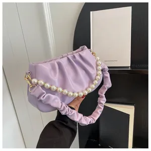 Detailed close-up of lavender pleated cloud bag with elegant white pearl chain strap