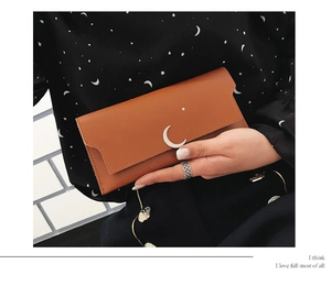 Détail du portefeuille en cuir caramel avec croissant de lune et étoiles dorées