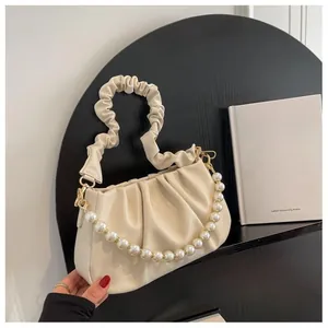 Detail of cream pleated cloud bag featuring ruffle handle and large faux pearl chain strap